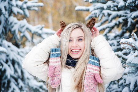 美丽的微笑的女人手里拿着一个松果。 室外下雪的天气。 生活方式。 寒假。