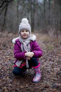 小可爱的女孩正坐在秋天森林的小路上