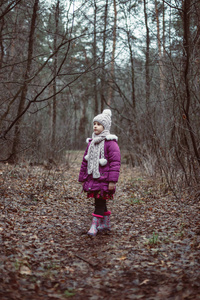 一个小女孩站在森林里的小径上