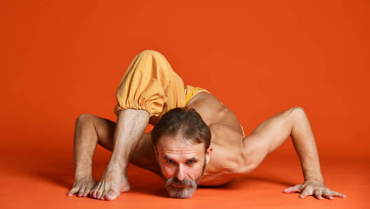 工作室拍摄的高级胡子男子做瑜伽姿势和伸展他的腿上身