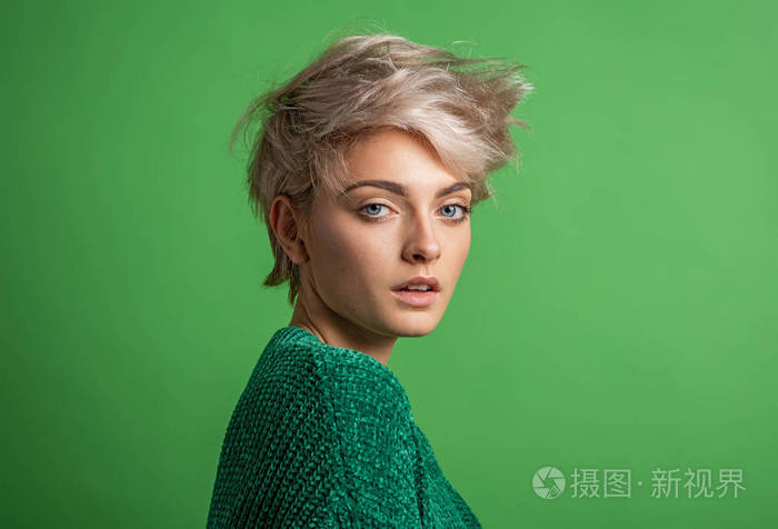 年轻女性的时尚肖像,金色短发,绿色背景