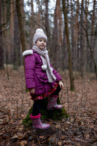 秋天森林里的小女孩在老树桩附近摆姿势