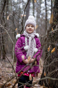 在秋天的森林里摆姿势的小可爱女孩。