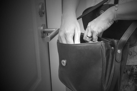 女人在公寓前的手提包里找钥匙之类的东西.黑白色调照片
