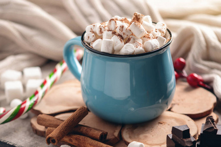 一杯热巧克力，上面有棉花糖和一根棒棒糖棒在针织毛毯背景上。 舒适温暖的冬季乡村构图
