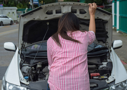 女人和坏车在路上检查发动机的问题。 事故和故障与汽车概念。