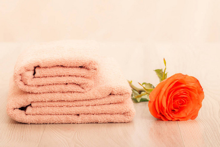 一叠柔软的特里毛巾，粉红色背景上有红色玫瑰花。