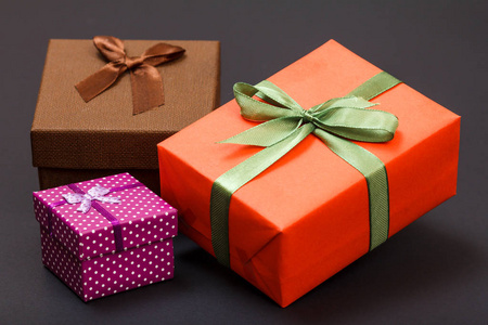 礼品盒系在黑色背景上的绿色红色和棕色丝带。 庆祝日的概念。