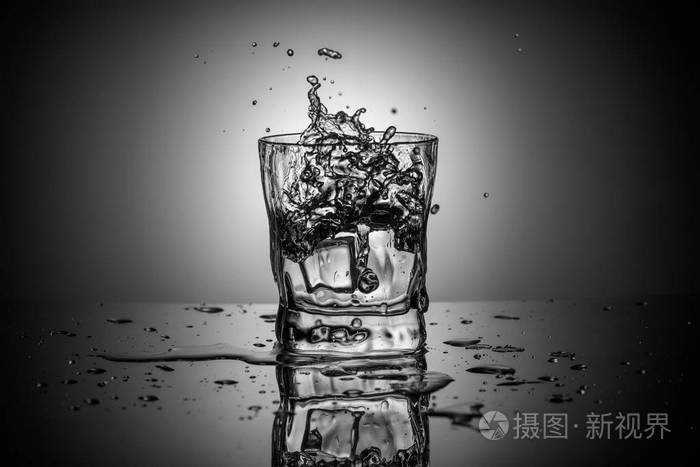 黑白拍摄水溅在优雅的威士忌玻璃梯度背景上