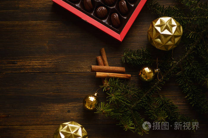 圣诞冷杉树枝，木桌上放着一盒糖果和金饰品