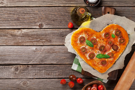 带有西红柿和马扎雷拉的心形披萨。 情人节贺卡。 顶部视图与您的文本空间