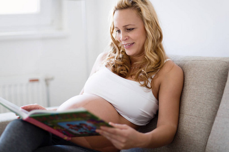 孕妇在家休息，在沙发上看书