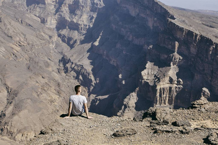 躺在悬崖边的年轻游客。 杰贝尔阿克达尔阿曼大峡谷