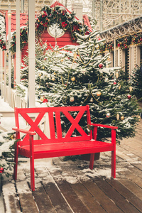 传统的装饰红色长凳，在城市博览会上放松。 夜光。 圣诞节。 下雪了。