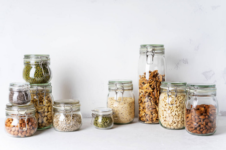 各种坚果，豆类和种子在玻璃罐中的光背景