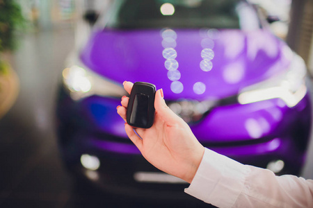 女性举行汽车钥匙与汽车在背景紫色颜色