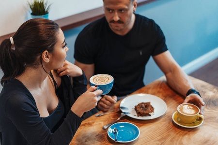 年轻夫妇坐在咖啡厅在约会, 喝咖啡和吃甜点