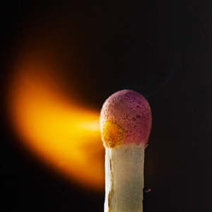 燃烧的木制火柴,黑色背景上有一个红色的火柴头. 近点照片