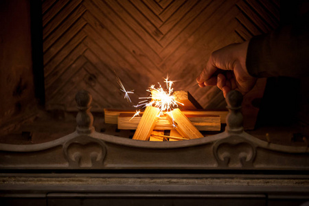 集火花在一堆木火堆上的旧壁炉里,一只手握着燃烧的火花摄影图
