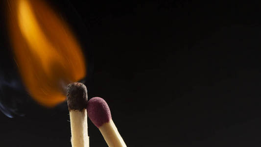 燃烧的木制火柴,黑色背景上有一个红色的火柴头. 近点照片