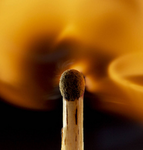 燃烧的木制火柴,黑色背景上有一个红色的火柴头. 近点照片