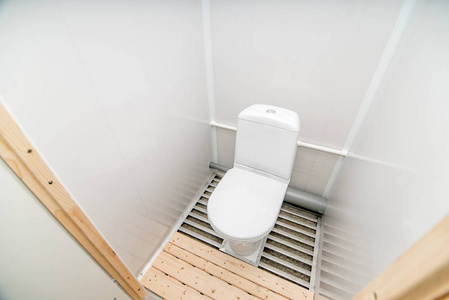 明亮的公共厕所房间的照片，里面站着一个白色的马桶