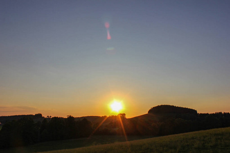 德国南部的日落黄昏，地平线上有树木和绿草地草地景观