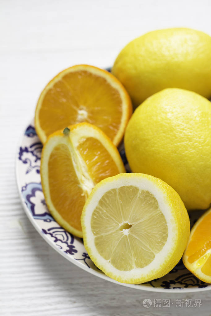 在白色背景下的盘子里放橘子和柠檬