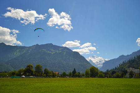 滑翔伞山脉的轮廓覆盖着森林蓝天和云绿的草地。 入侵瑞士。