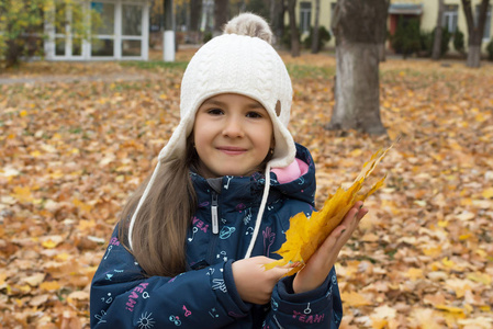 秋天美丽的小女孩的肖像，有一束黄叶