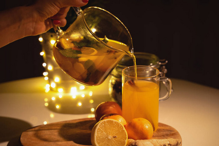 在一个杯子里的辛辣茶与肉桂, 蜂蜜, 姜黄在木制的背景。热饮料。复制空间。圣诞灯饰