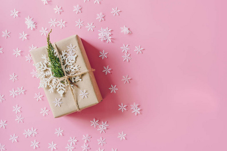 棕色礼品盒的粉红色背景与圣诞节装饰。 最小风格的假日卡与复制空间。