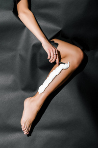 女孩剃须刀腿用黑色纸孔切割的图像