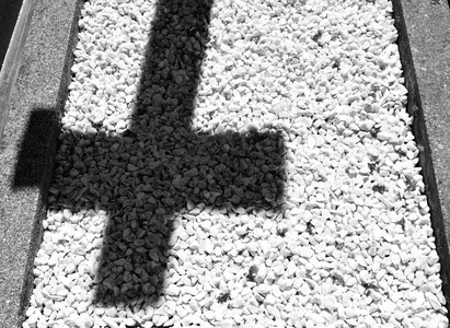 墓地白色小石头地板上十字架的影子悲伤和悲伤的概念。 黑白的。