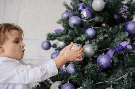 一个6岁的金发男孩用塑料玩具装饰圣诞树