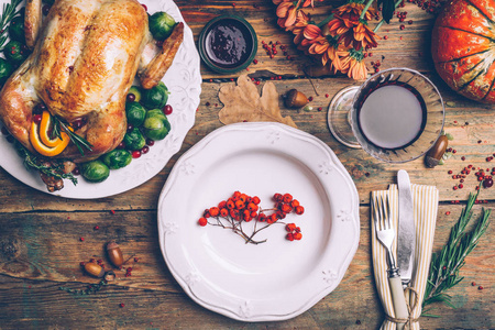 烤鸡与甘蓝芽和香料在乡村木制桌子上。 感恩节晚餐或秋季晚餐概念背景与秋叶。 感恩节桌子设置背景。