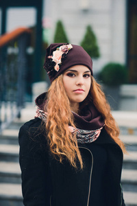 在秋天的天气里穿着温暖的衣服和帽子的滑稽的年轻女孩的肖像