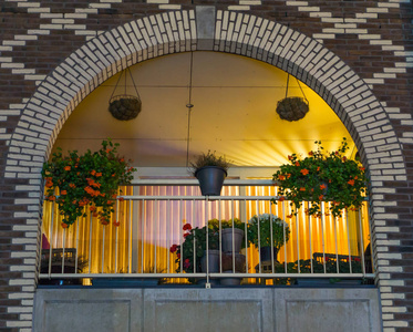 美丽的拱形荷兰阳台，夜间装饰鲜花，现代城市建筑和建筑