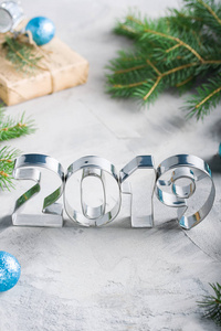 新年快乐2019构图与金属字母球杉树工艺礼品盒在蓝色灰色混凝土背景。 贺卡。