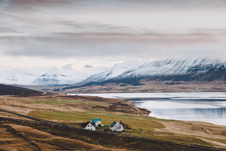 村庄有农场在冰岛山区的农村地区，背景是雪山。