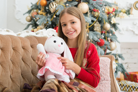 小孩玩软玩具.小女孩与可爱的兔子在圣诞树上.小女孩拿着兔子玩具.