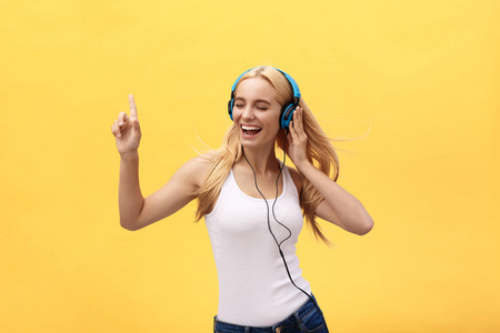 生活方式一个快乐的妇女的肖像听音乐在耳机孤立的黄色背景