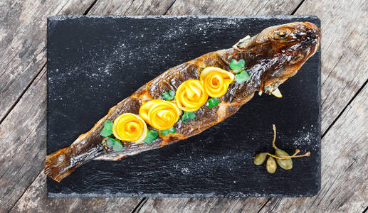 烤海鱼与柠檬在石板背景接近。 健康的食物。 顶部视图