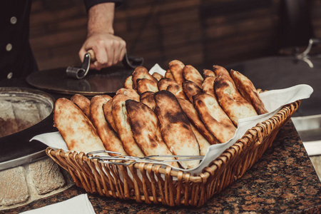 面包师在坦多尔粘土烤箱制作土耳其皮塔面包。 烘焙过程。 篮子里有许多新鲜的热面包