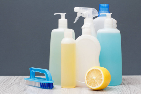 塑料瓶的洗碗液，玻璃和瓷砖清洁剂，用于微波炉，炉子，刷子和柠檬在灰色背景。 洗涤和清洁的概念。