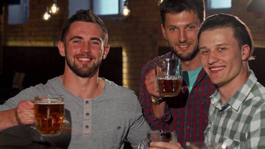 一群朋友在酒吧里拿着啤酒杯对着镜头微笑