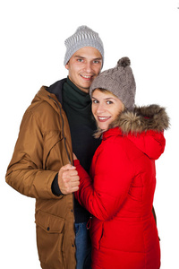 年轻夫妇穿着红色和棕色的冬装外套，在孤立的背景下摆出季节性服装