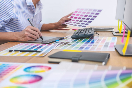 男性创意平面设计师的形象，致力于颜色选择和绘制图形平板在工作场所与工作空间的工作工具和附件。
