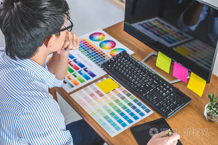 男性创意平面设计师的形象,致力于颜色选择和绘制图形平板在工作场所