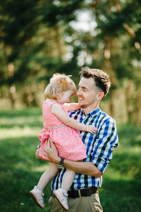女儿在暑假拥抱父亲。 日落时爸爸和女孩在公园里玩。 友好家庭的概念。 特写镜头。